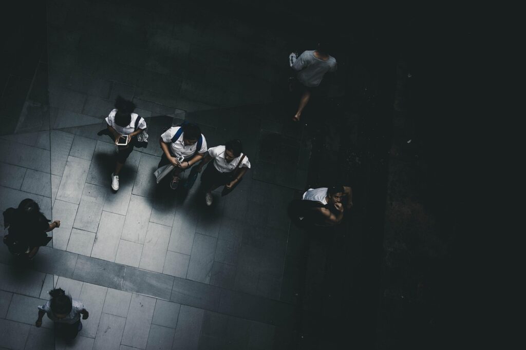 a imagem mostra um corredor de uma escola, cheio de adolescentes, todos com celulares, porem não interagem, cada um com seu celular. O corredor esta com uma cor acinzentada, sem vida, pois mesmo cheio ninguém esta conversando, serve pra refletirmos de como as redes socias e o excesso de tecnologia, causam um impacto na saúde mental e social dos nossos adolescentes